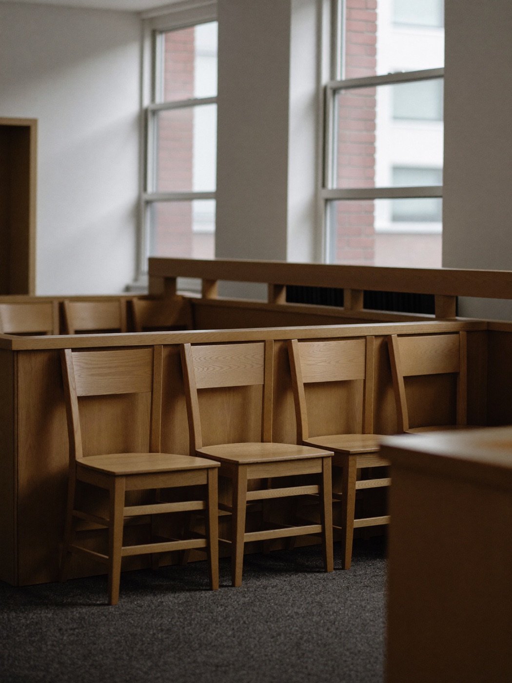 Empty wooden jury box in a quiet courtroom, twelve seats in two rows